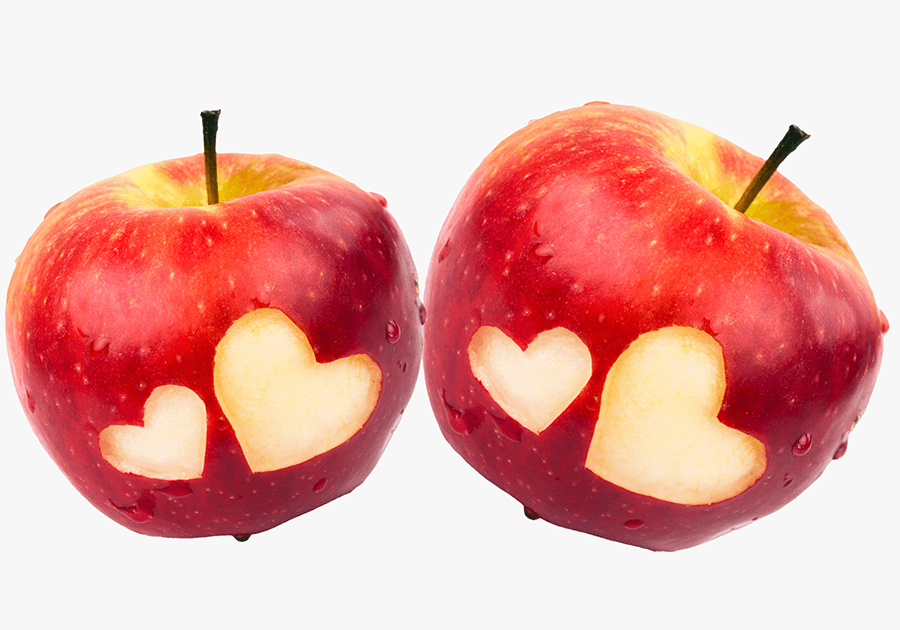 Två röda äpplen med hjärtan urskurna i skalet